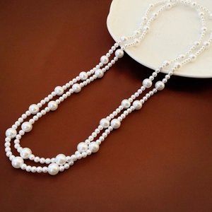 Detailed view of layered long pearl necklace with high luster on a vintage brown background