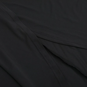 Detailed close-up of the black knitted fabric stitching and side slit on the dress