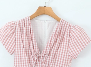Vue détaillée d'une robe à carreaux rose et blanc avec col en V et nœud délicat