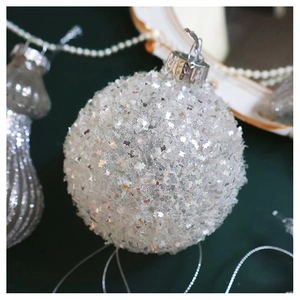 Detail of silver Christmas tree ball with shiny star sequins and glitter on green fabric