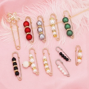 Fashionable pearl waist cincher pins with crystals displayed on pink silk background