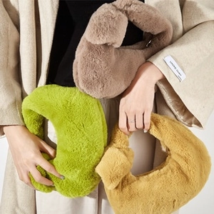 Three plush knotted handbags in green, coffee, and yellow shown by hand with a soft coat