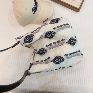 Detailed embroidery on white linen tote bag with geometric floral patterns and leather strap