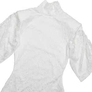 Detailed close-up showing intricate floral lace texture and stand collar of the white bodysuit
