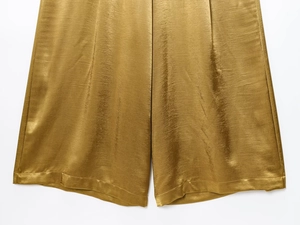 Detailed macro view showing the silky texture and golden luster of satin wide-leg pants