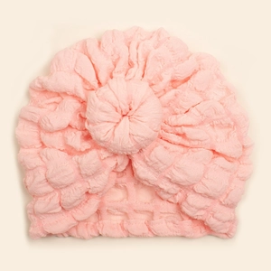 Detailed view of pink baby donut turban hat with pleated soft fabric texture