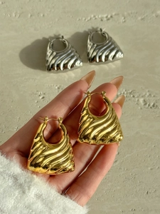 Macro shot of vintage style hollow trapezoid gold and silver wave texture earrings