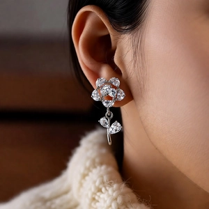 Close-up of elegant silver flower earrings with zircon petals worn by a model