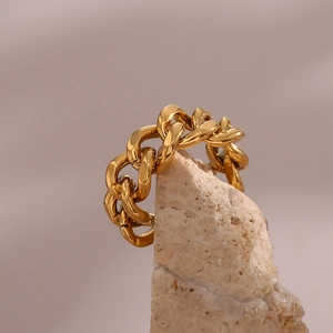 Macro shot of gold stainless steel Cuban link ring on a natural stone background