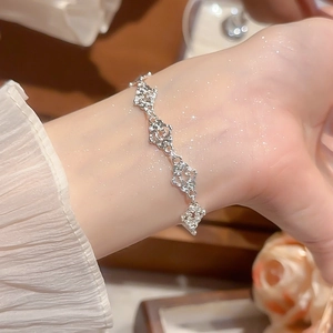 Detailed view of silver hollow patterned heart bracelet on wrist with elegant lace sleeve