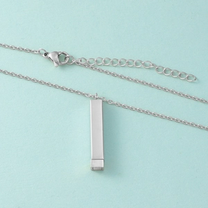 Détail du pendentif rectangulaire en acier inoxydable argenté sur une fine chaîne