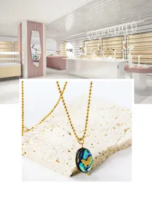 Macro detail of abalone shell pendant necklace with gold butterfly emboss on ball chain