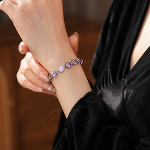 Macro detail of round purple zircon bracelet with silver-tone metal links on wrist