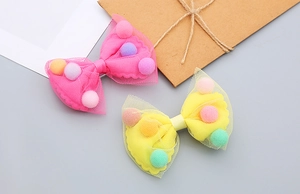 Detail of pink and yellow mesh hair clips featuring colorful pom poms for girls