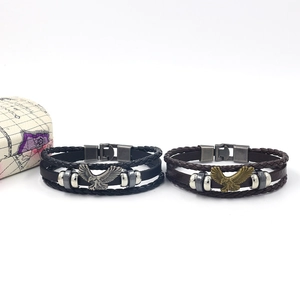 Dettagli di bracciali in pelle intrecciata multistrato con ciondoli aquila in argento e bronzo