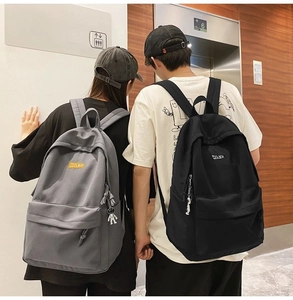 Close-up of gray and black backpacks with COOL BOY labels and astronaut pendants