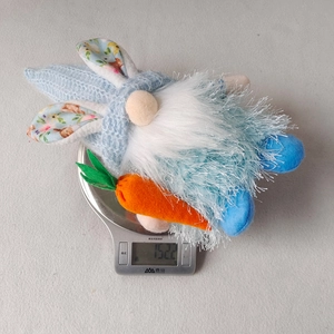 Easter gnome plush toy with bunny ears holding a carrot shown on an electronic scale