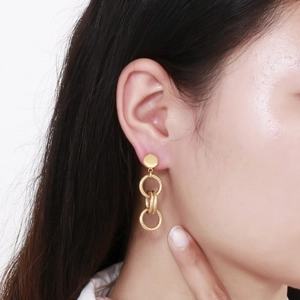 Gros plan de boucles d'oreilles pendantes à trois anneaux dorés portées par un mannequin