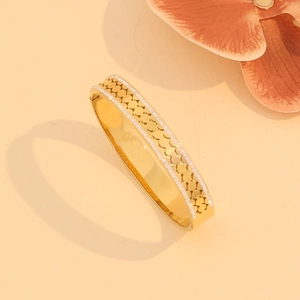 Detail of gold crystal-paved镂空 bangle with fish scale pattern on a beige backdrop