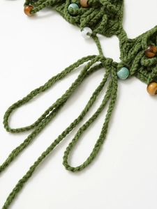 Close-up of green hand-knit crochet beachwear with colorful mineral beads and tie straps