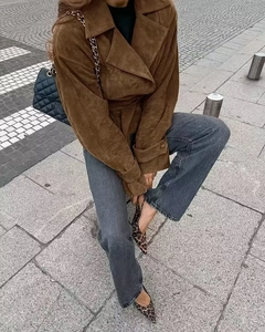 Detail of a brown suede short jacket with lapel collar shown in an outdoor street setting