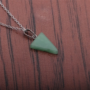 Green triangular stone pendant necklace with silver metal chain on wood background