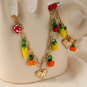 Golden charm bracelet featuring colorful fruit pendants and zircon hearts on a model wrist