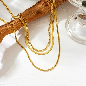 Three-layer gold stainless steel necklace with snake, cable and figaro chain on wood