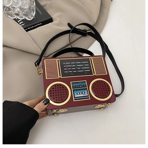 Detail of red radio-shaped acrylic box bag with gold hardware on lifestyle background