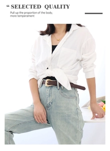 Detail of dark brown leather belt with gold geometric buckle worn over blue jeans