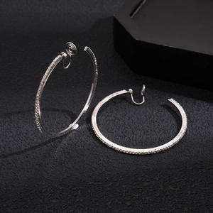 Macro shot of silver circular clip-on earrings with pave diamonds on dark texture