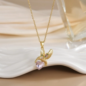 Detail of gold hummingbird pendant with colorful crystals and heart-shaped pink stone