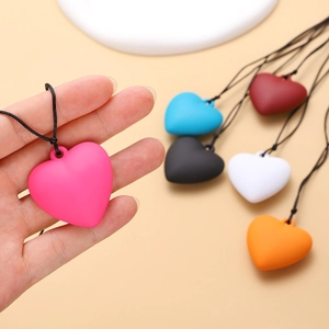 Vue macro de pendentifs cœur évidés mats en plusieurs couleurs avec cordon noir