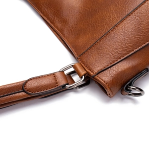 Detail of brown litchi grain leather texture and dark gunmetal hardware on the handbag