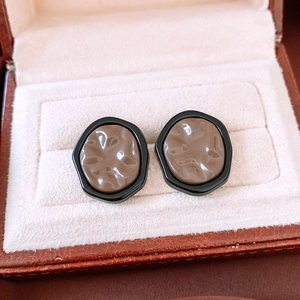 Macro detail of French vintage earrings with textured brown resin in a jewelry box