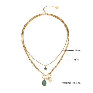 Close-up of double-layer gold necklace with turquoise stone and tree of life charm
