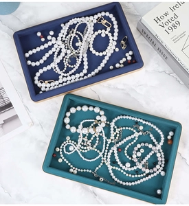 Blue and green jewelry display trays showing pearl necklaces on marble surface