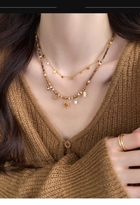 Detail of layered sun and star beaded necklace with tiger eye stones on brown sweater