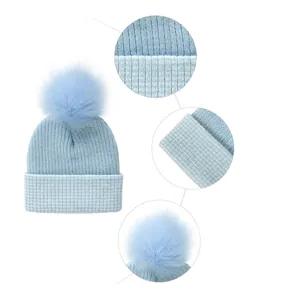 Striped light blue knit beanie for babies featuring a large faux fur pom-pom and folded cuff
