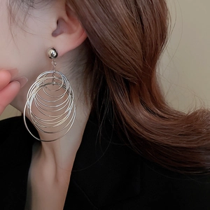 Side view of multi-layer silver hoop earrings with metallic finish on a female model