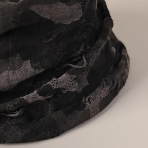 Macro shot of dark grey camouflage knitted fabric with distressed ripped texture and fibers