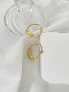 Macro detail of crescent moon earrings with rhinestones and matte gold finish