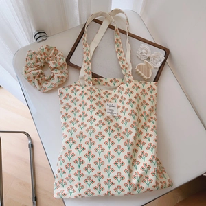 Detail of floral canvas tote bag and matching scrunchie on a styled white desktop