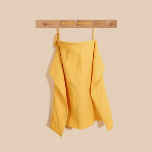 Detailed waffle weave texture of a mustard yellow cotton nursing cover with neck strap