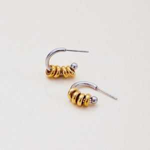 Detail of two-tone stainless steel hoop earrings with gold rings and silver beads