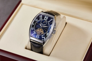 Detail of tonneau-shaped mechanical watch with blue dial and leather strap in a gift box