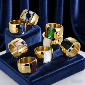 Close-up of golden wide-band rings featuring square-cut glass stones in various colors