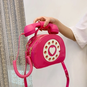 Close-up of pink patent leather telephone bag with heart-shaped dial and spiral cord handle