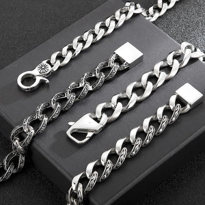 Close-up of silver Cuban chain and vintage black engraved link bracelets for men
