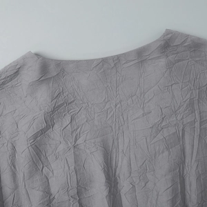 Détail du tissu gris plissé avec texture gaufrée et col rond sur la robe élégante